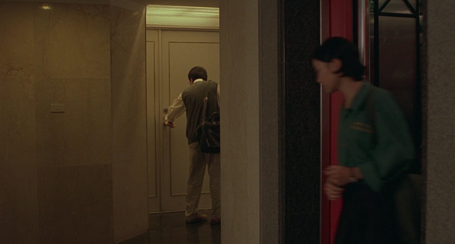 Ting Ting gets off an elevator as a man exits an apartment right outside of the elevators in Edward Yang's movie Yi Yi. 