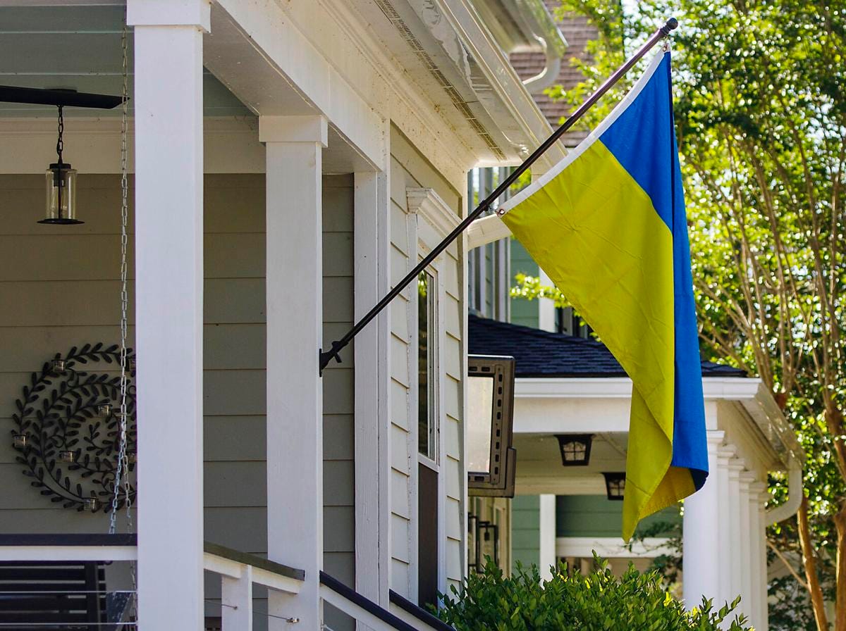 A blue and yellow flag hangs in front of a suburban home