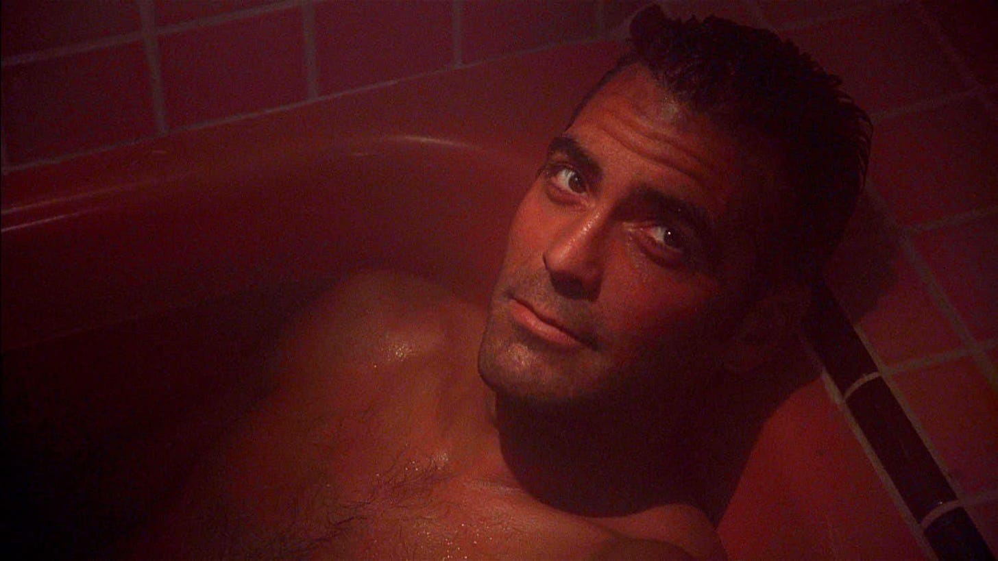 head and chest of naked clooney in bath, looking up soulfully