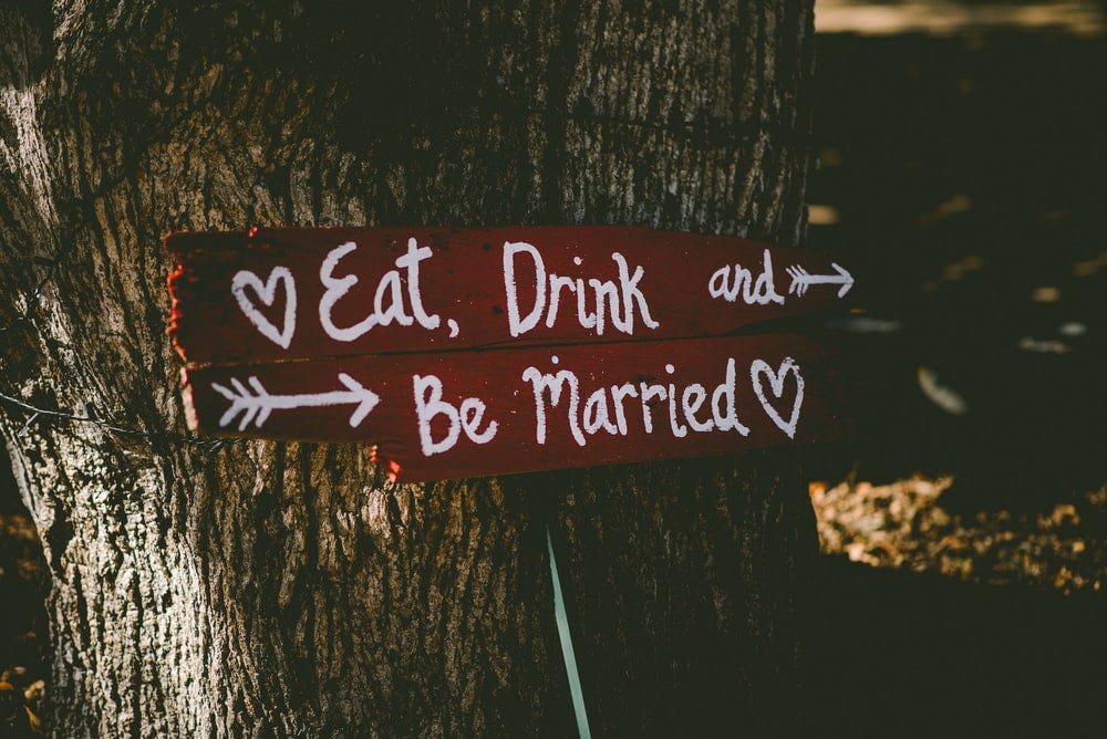 red and white eat, drink, and be married signage near brown tree red and white eat, drink, and be married signage near brown tree