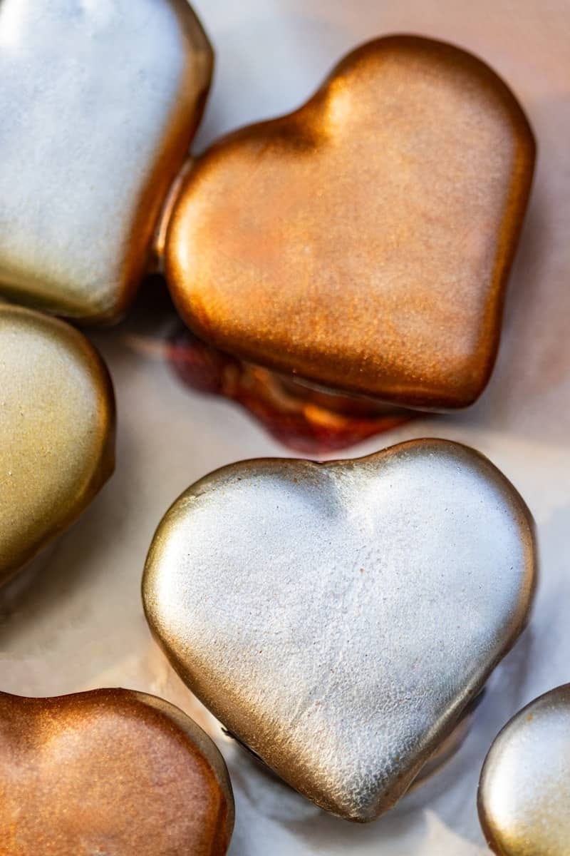 Shiny, metallic heart-shaped chocolates are beautifully arranged.