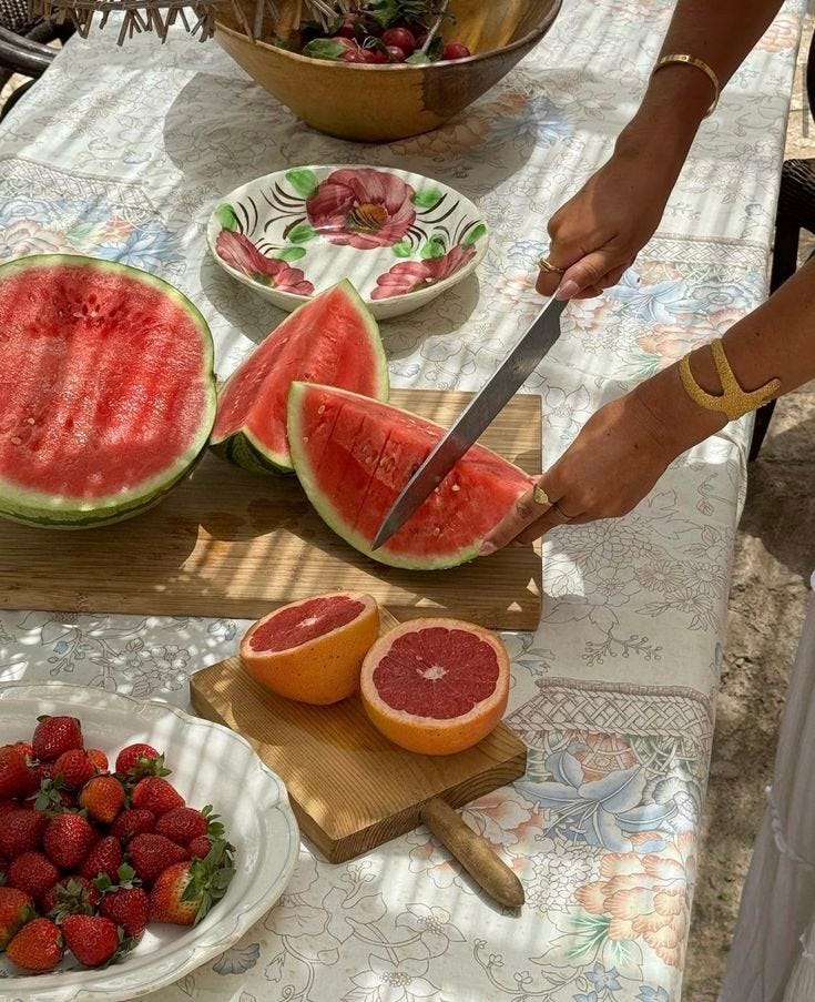 This may contain: a person cutting up watermelon slices on a table with strawberries and strawberrys