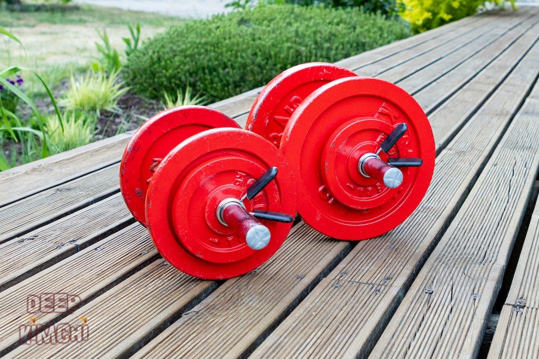 two red dumbbells sitting on a wooden table