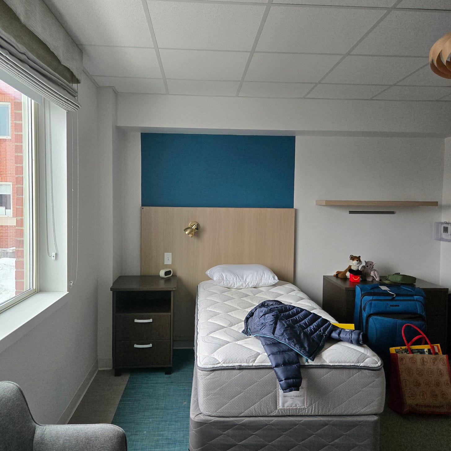 A single bed in a basic room next to a window A single bed in a basic room next to a window