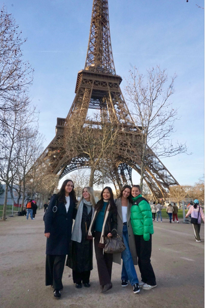 A group of women posing for a picture in front of a metal tower

AI-generated content may be incorrect.