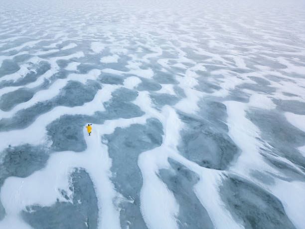 lone explorer walking on frozen lake covered with snow and ice - snowdrift stock pictures, royalty-free photos & images