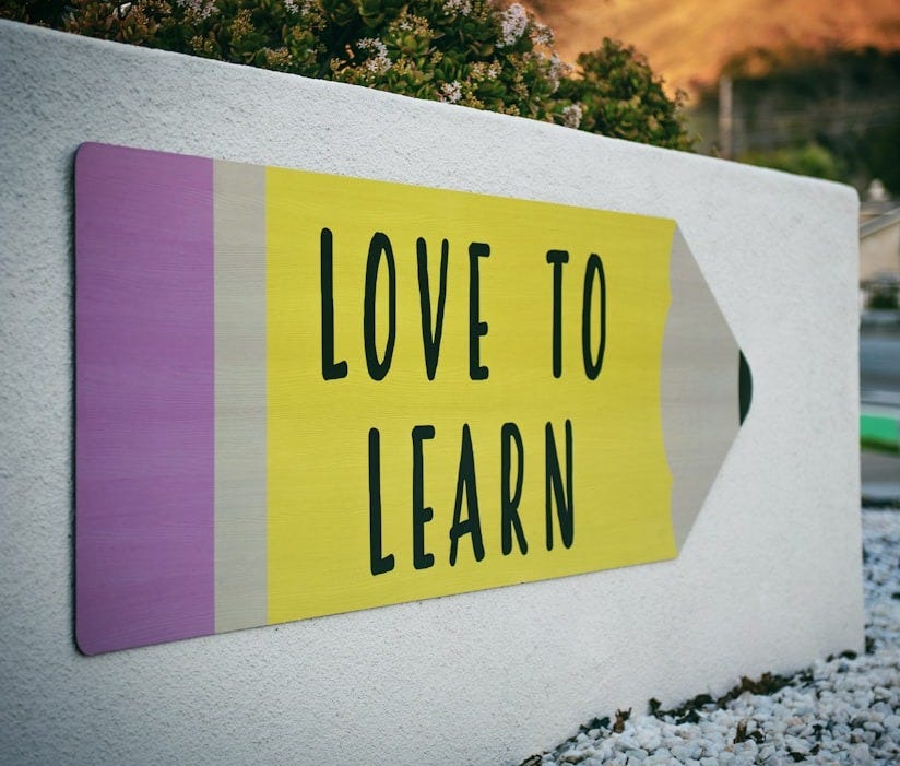 love to learn pencil signage on wall near walking man love to learn pencil signage on wall near walking man