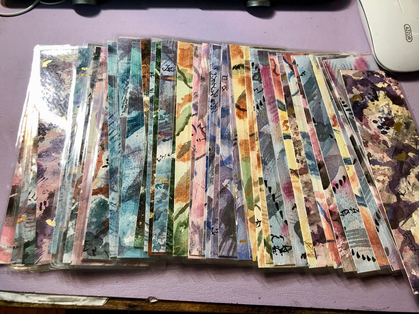 A pile of colourful abstract art bookmarks are spread out over the surface.