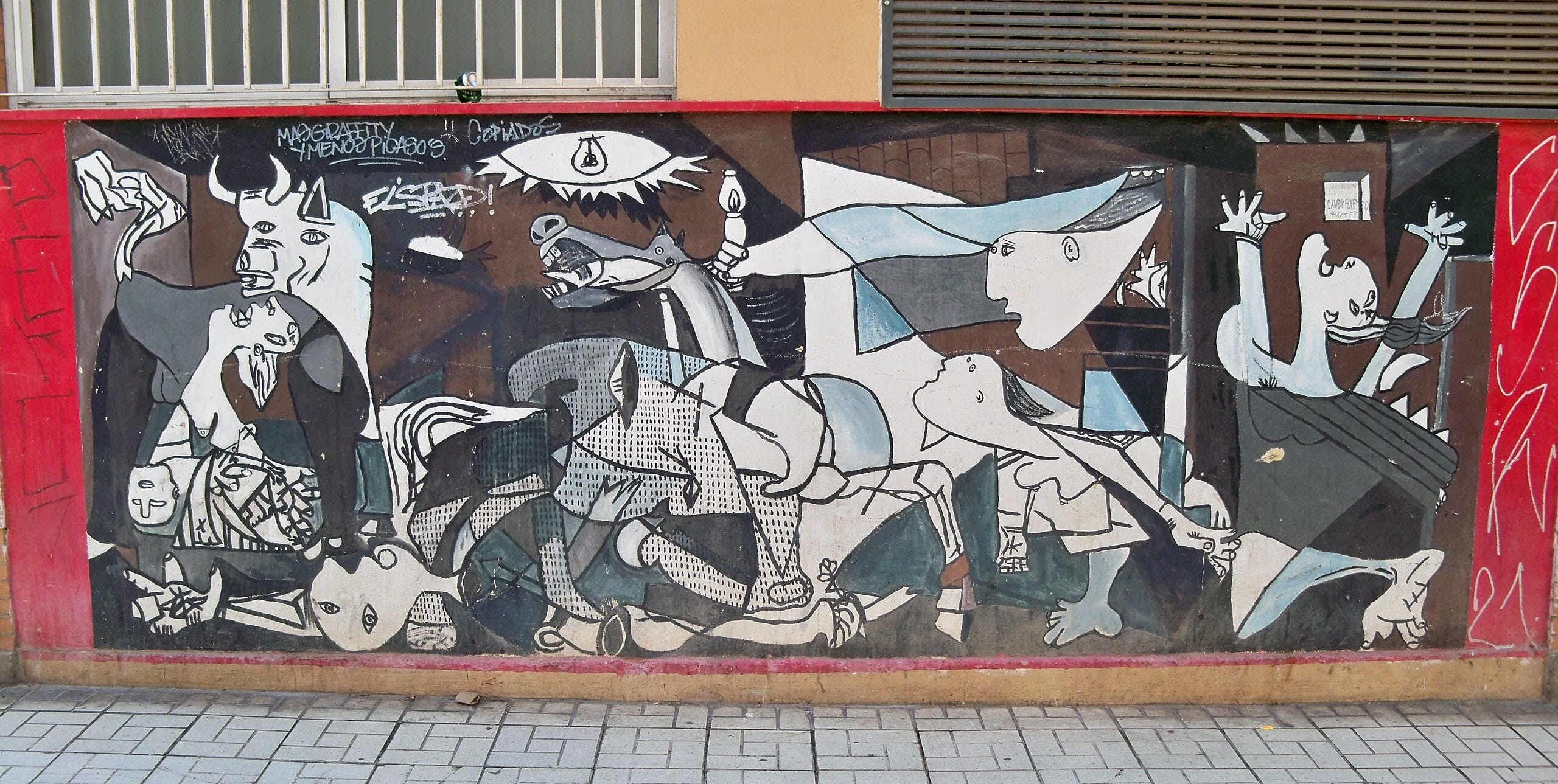 A mural replicating Picasso's "Guernica" on a red wall, meshed with small graffiti tags.