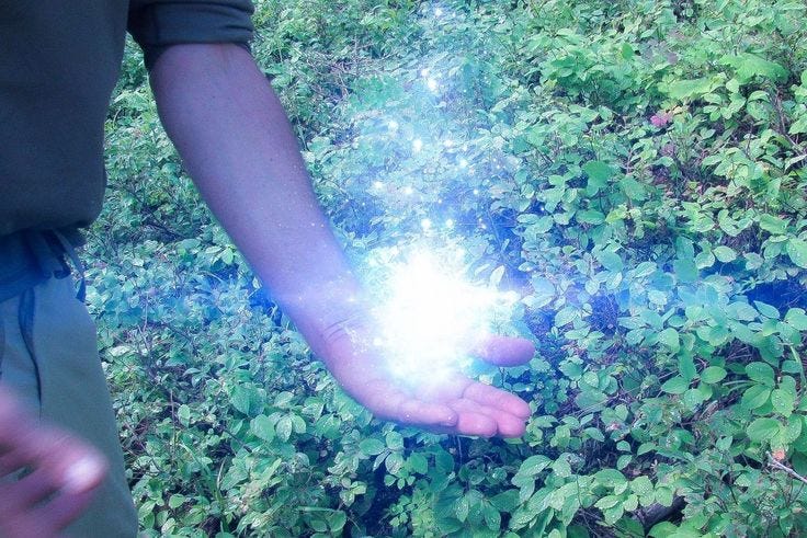 This may contain: the person is holding out their hand to light up something in the grass and bushes