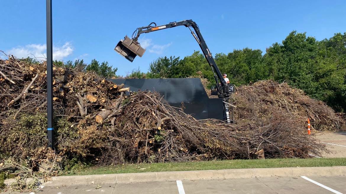 A claw truck sorting humongous piles of storm debris