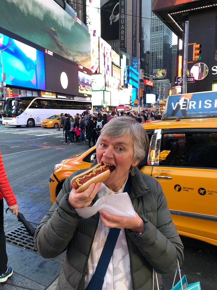 two women smiling outside a theatre and a woman eating a hotdog