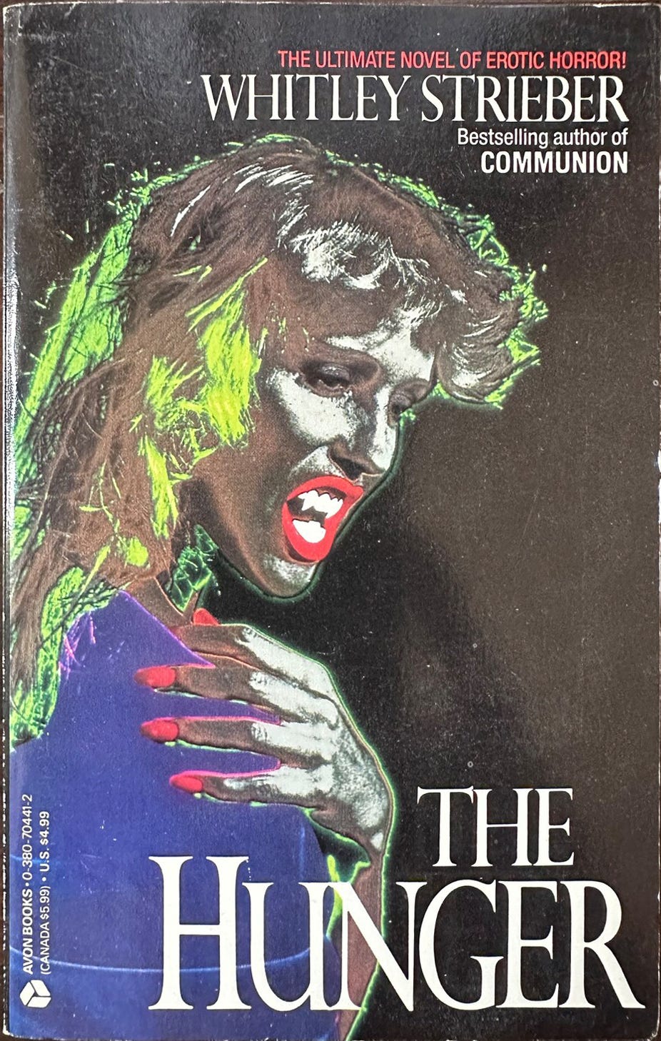 High-contrast spot-toned photo of a woman with vampire fangs and long pointy red fingernails