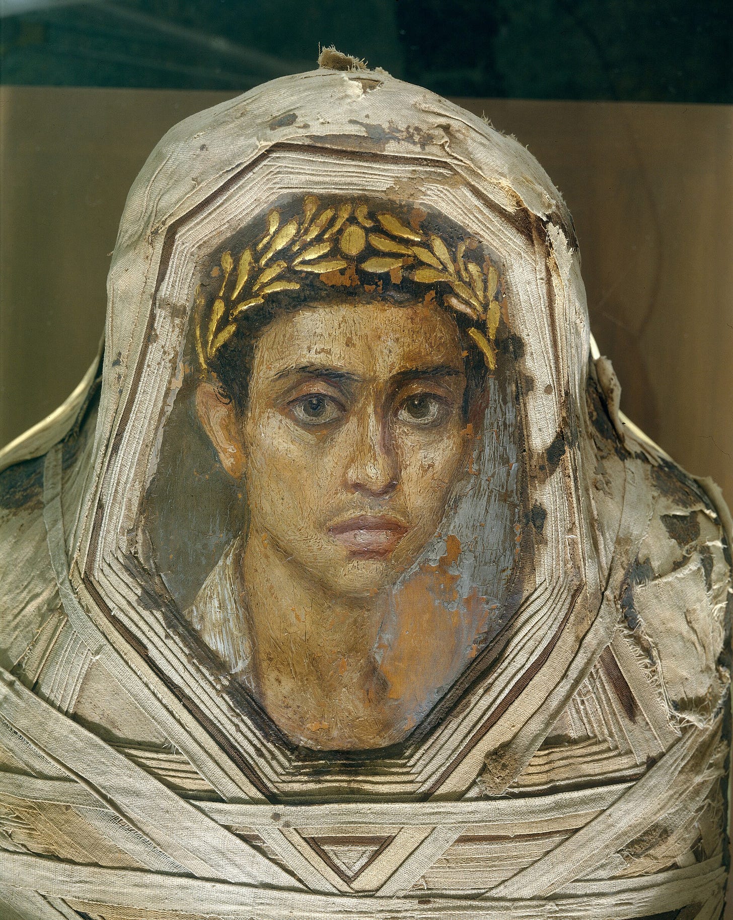 Mummy with an Inserted Panel Portrait of a Youth, from Hawara, Egypt, 80 to 100 CE, encaustic on limewood. Metropolitan Museum of Art, New York.