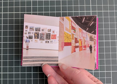 image 1; a small booklet held in a woman's hand, the cover is magenta pink with a black map pin in the center and the words "my two cities" in white. image 2, a woman's hand holds up the booklet, the spread shows to similar photos. the photo on left shows a large flowering tree with bright pink and white blooms behind the tree is a house with faded yellow wood siding, on the right the photo shows a small flowering tree with bright pink and white blooms, behind the tree is an apartment building made of pale yellow stucco. image 3, a woman's hand holds open the booklet, the spread shows two similar photos. the photo on the left shows a gothic archway through the archway we see stairs leading up to trees and a lone figure silhouetted, the photo on the right shows a tall carved stone archway, there are people in the foreground and through the archway we see a pale sky a long statue silhouetted. image 4, a woman's hand holds up the booklet, the spread shows two similar photos, the photo on the left shows various posters and flyers interspersed with graffiti on a dark brown door, the photo on the right shows a wall completely covered in flour pasted flyers and posters. image 5, a woman's hand holds up the booklet, the spread shows two similar photos, the photo on the left shows an iced coffee drink in a plastic cup and a iced blueberry scone on.a black napkin on a rustic wood table with an empty wood cane chair in the background, the photo on the right shows an iced coffee drink in a glass mason chair and a croissant covered in powdered sugar on a black stone tray sitting on a smooth wooden table, there's am empty white woven chair in the background. image 6, a woman's hand holds up the booklet, the spread shows two similar photos, the image on the left shows the tops of trees and small homes and flat top apartment buildings, the sky is pale yellow and blue and a few dark blue clouds dot it, the image on the right shows the tops of white homes and apartments with dark red terracotta shingles on the roofs, the sky is pale blue and yellow with dark blue and bright pink clouds. image 7, a woman's hand holds open the booklet, the spread shows two similar photos, the photo on the left shows a white gallery wall featuring many framed art works in varying sizes and shapes. a long man in a khaki shorts and blue shirt stands to the left looking up at the artwork, the photo on the right shows a large beige curved wall featuring many hanging loose canvases painted in bright warm colors, a lone man stands to the right in all black looking up at the canvases. image 8, a woman's hand holds open the booklet, the spread shows two similar photos, the photo on the left is a woman's left hand holding an ice cream cone with two scoops, the ice cream is white with brown flecks, the background shows a blurry concrete sidewalk, the photo on the right show's a woman's left hand holding an ice cream cone, the ice cream is dark chocolate and artfully arranged into petals to resemble a rose, the background is a blurry tiled sidewalk in white and black. image 9, a woman's hand holds open the booklet, the spread is two similar photos, the photo on the left is a bright blue sky with fluffy white clouds over the NYC skyline, the photo on the right shows the sky in the exact same bright blue shade with white fluffy clouds that seem to connect with the clouds from the photo on the left, the buildings at the bottom of the photo are white with bright red terracotta roofs