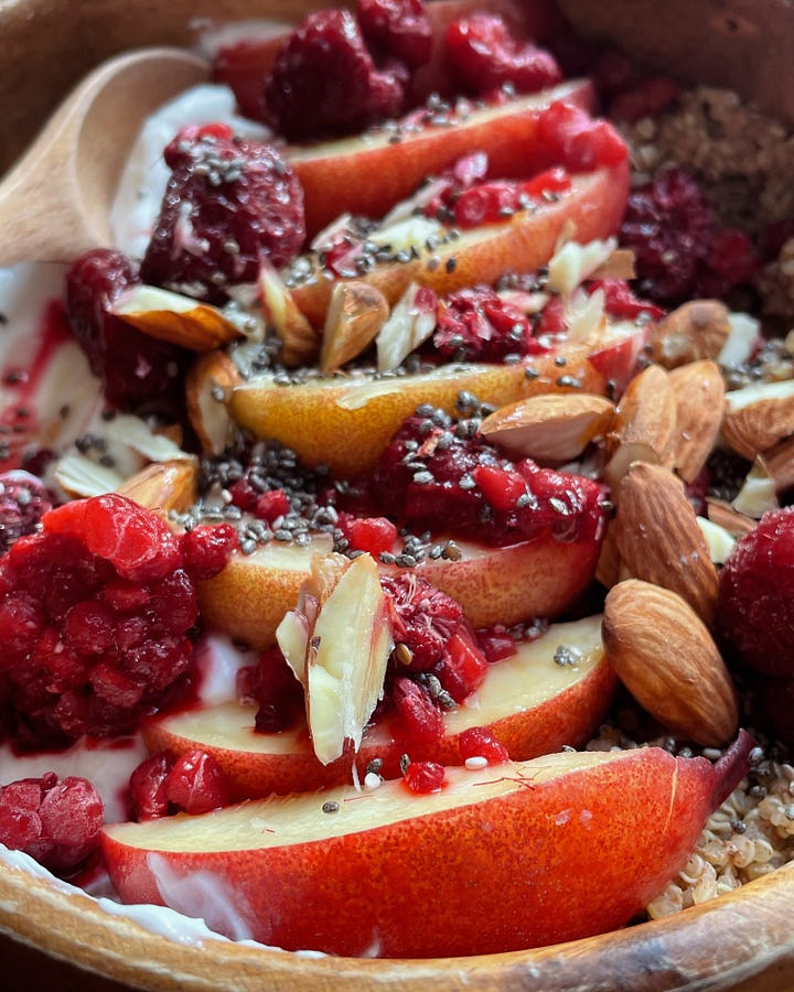 Gallery with 2 images. Image 1: A sunny breakfast desk scene with my cinnamon quinoa bowl and morning coffee. / Image 2: A close-up of raspberries, nectarines, almonds, and yoghurt-topped quinoa glowing in the sun.
