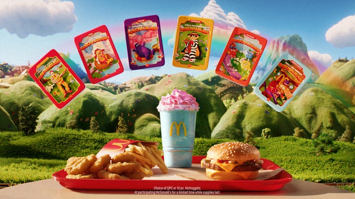 A McDonald's meal on a try surrounded by 6 floating tin images with nostalgic characters on them. The meal also features a blueish drink with pink cream on top