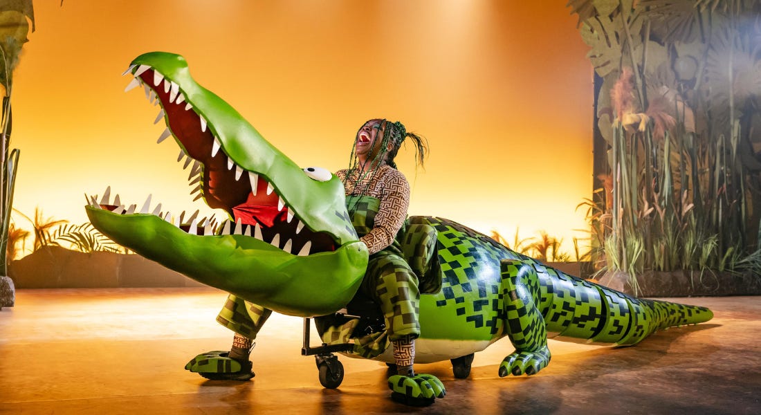 A woman - Chelsea Da Silva - on top of a crocodile puppet laughing