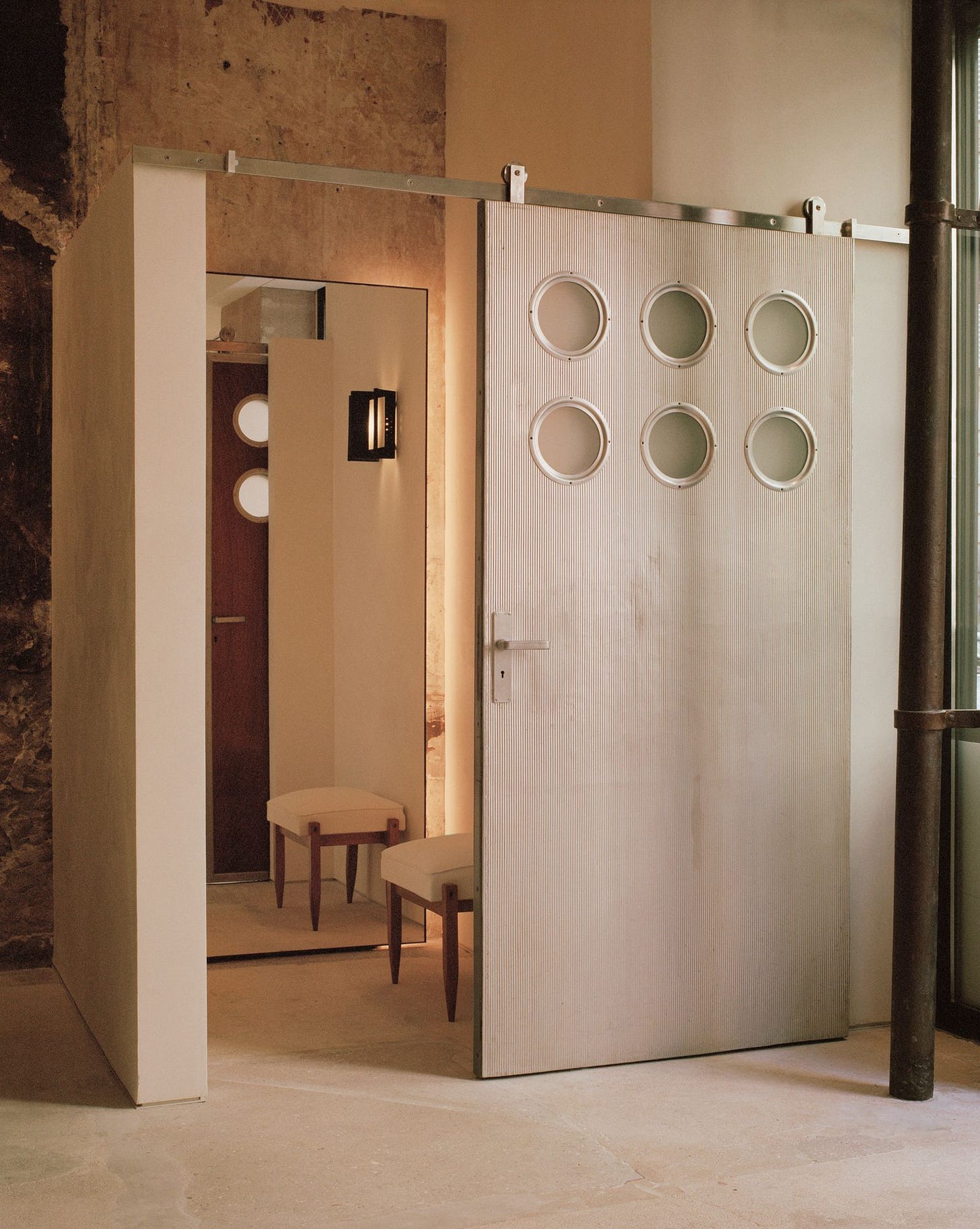 Vintage Jean Prouvé metal door installed inside The Row’s Paris store, framing a minimalist fitting room