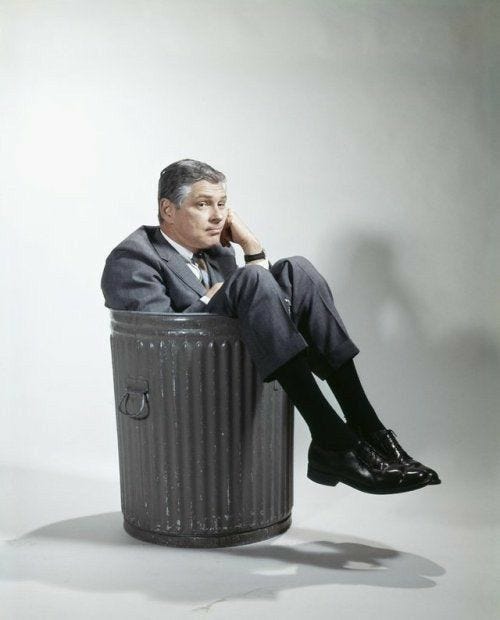 This may contain: a man is sitting in a trash can