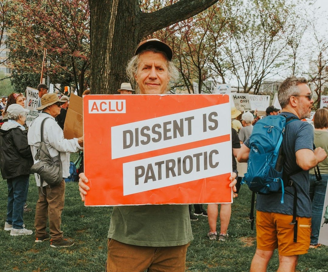 Man holds sign: "dissent is patriotic."