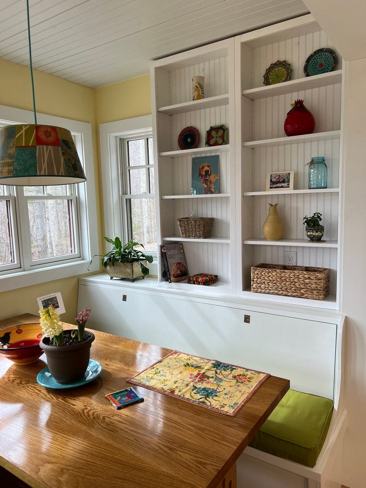 A kitchen built and designed by Equinox Woodworks, with human-scale windows and cozy cabinets situated behind a table placed inside a nook. A kitchen built and designed by Equinox Woodworks, with human-scale windows and cozy cabinets situated behind a table placed inside a nook.