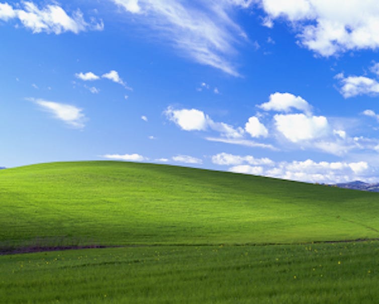 A colorful stock photo of green rolling hills, a blue sky and clouds.