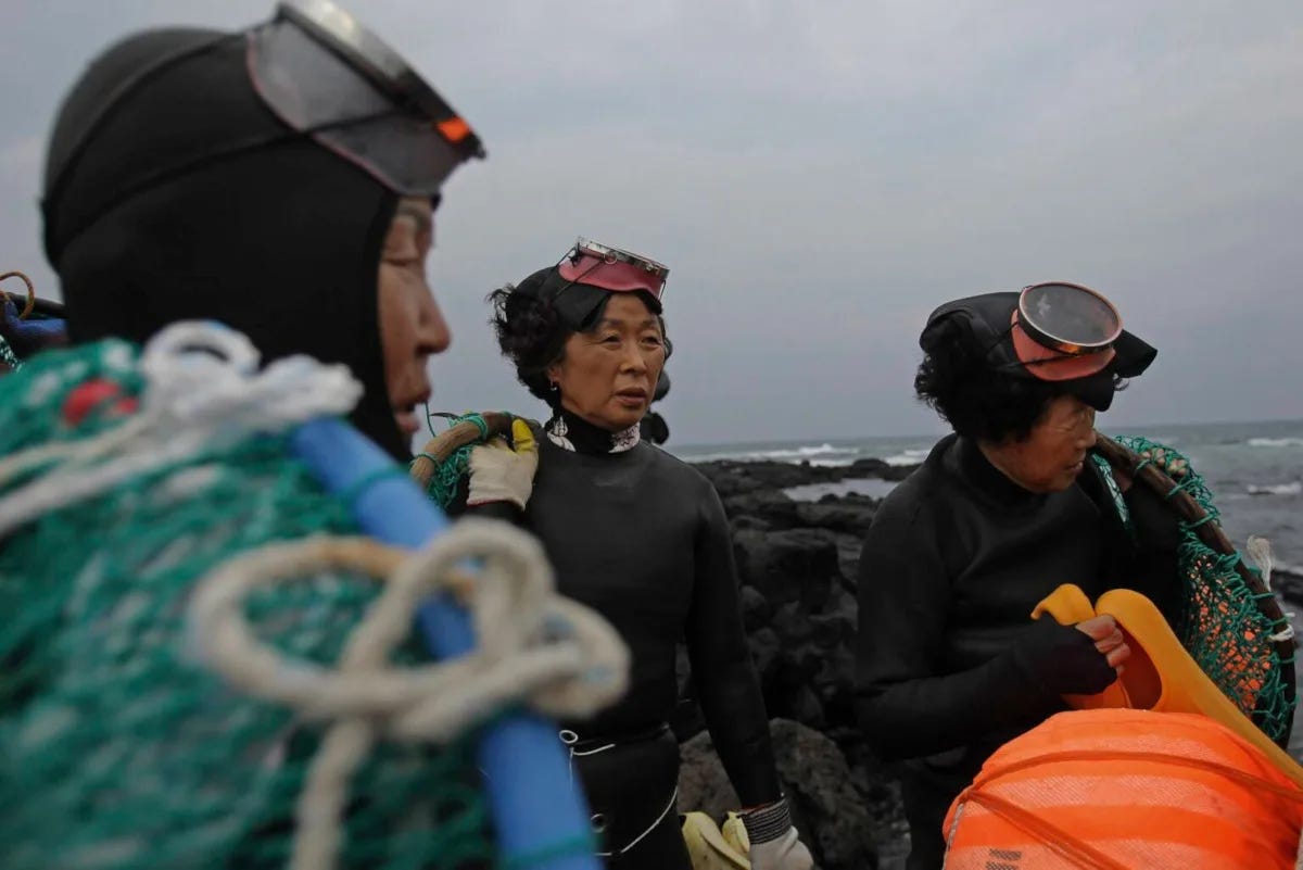 Photo of three elderly women from South Korea in wetsuits holding fishing gear. Photo of three elderly women from South Korea in wetsuits holding fishing gear.