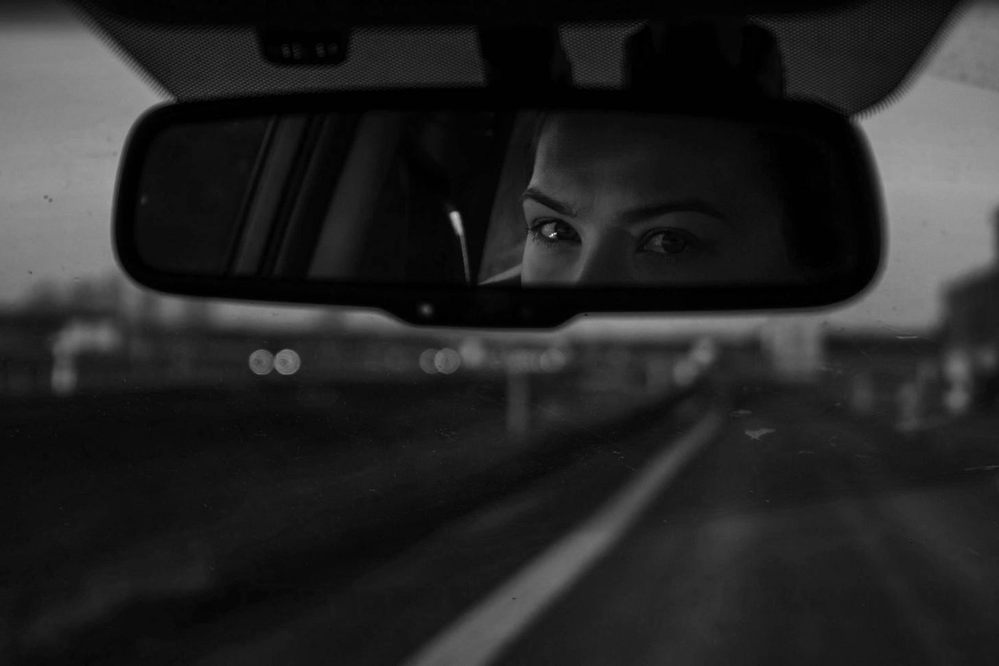 a woman's reflection in a rear view mirror a woman's reflection in a rear view mirror