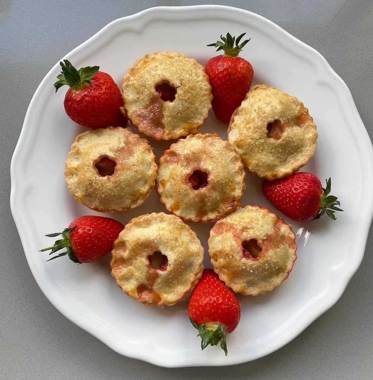 Plate of small apple and strawberry pies.