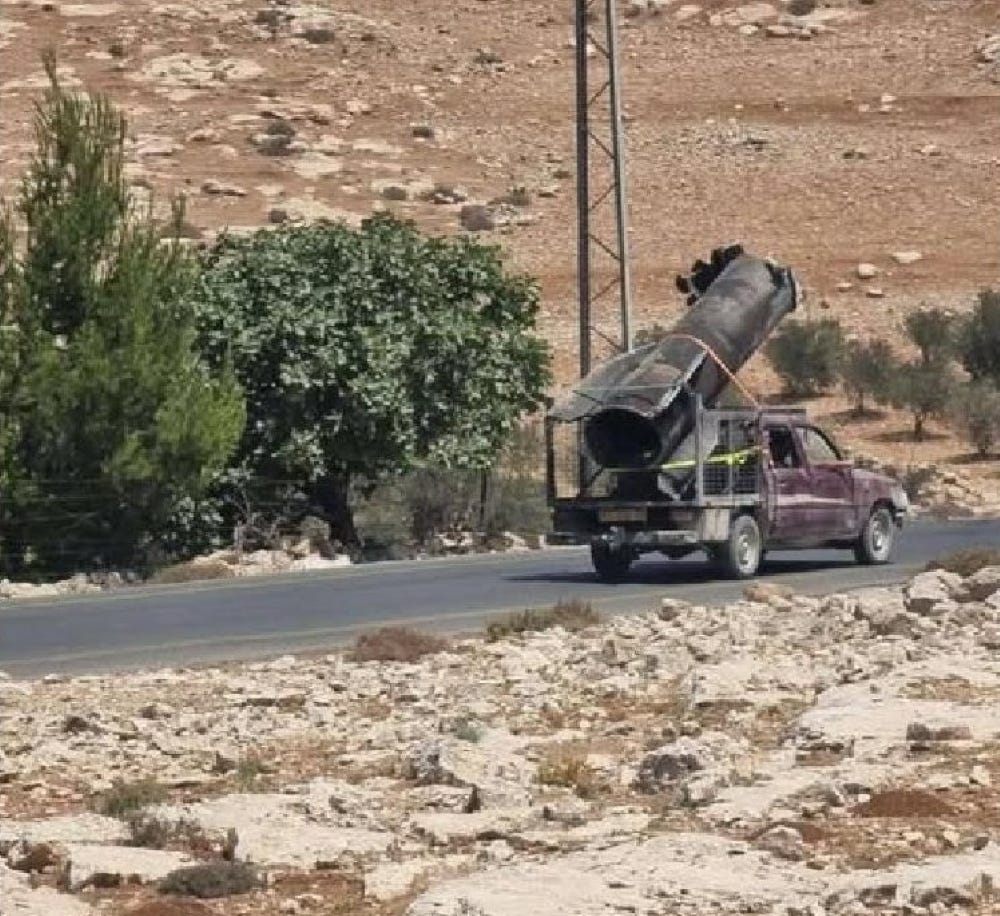 Dilapidated pickup truck with huge piece of a destroyed missile on a road through mountainous desert Dilapidated pickup truck with huge piece of a destroyed missile on a road through mountainous desert