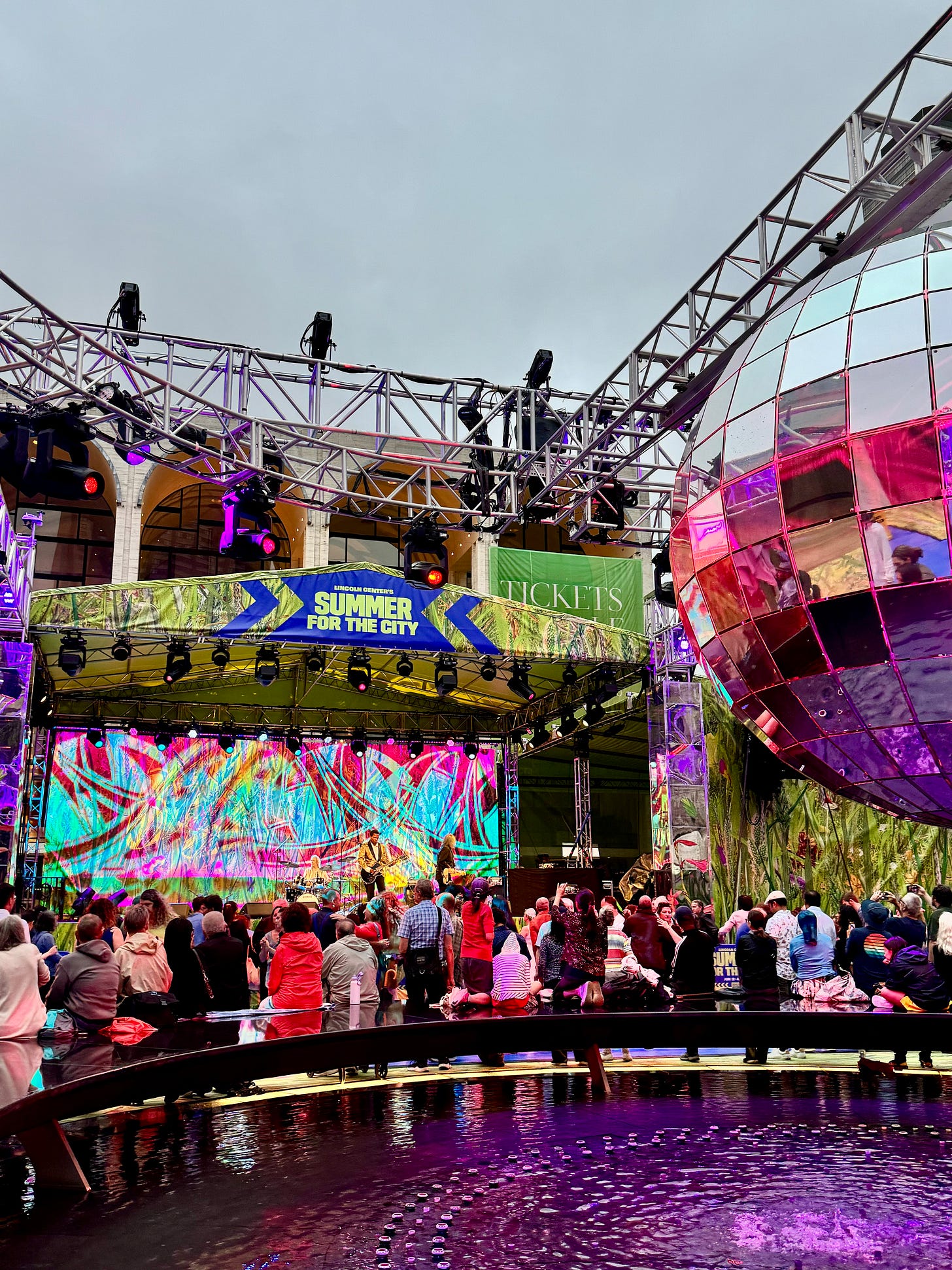 photo of Lincoln Center blues event. Big disco ball! Lots of people. Very grey sky. photo of Lincoln Center blues event. Big disco ball! Lots of people. Very grey sky.