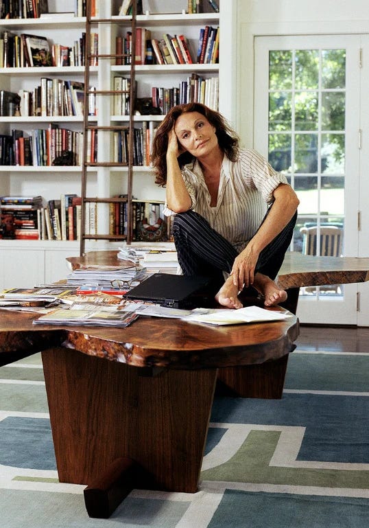 This may contain: a woman sitting on top of a wooden table in front of a bookshelf