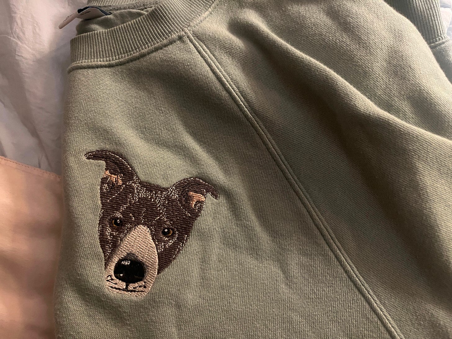 An upcycled Old Navy sweatshirt with a custom embroidery of Seymour the dog's face.
