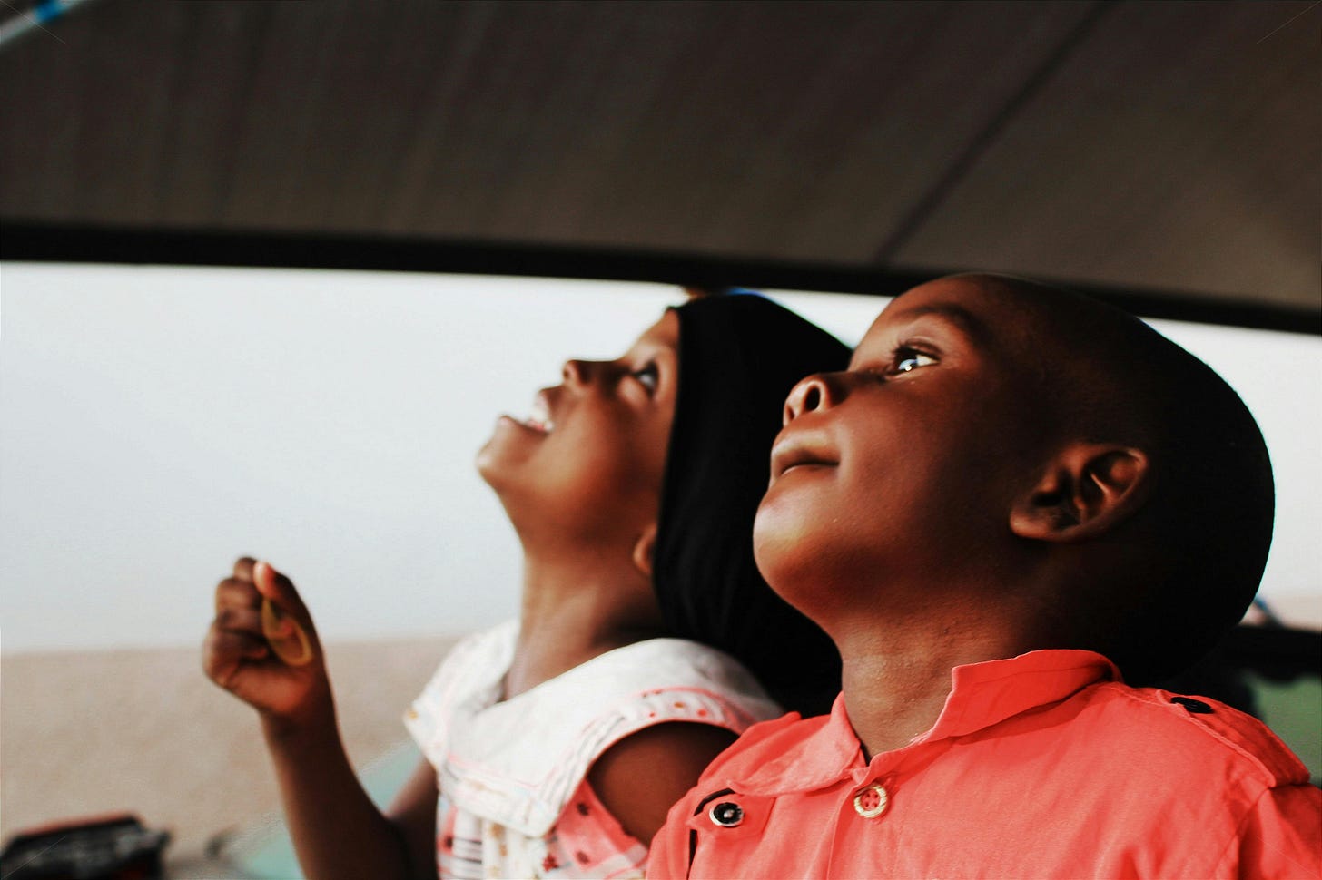 Two Black children smiling and looking up