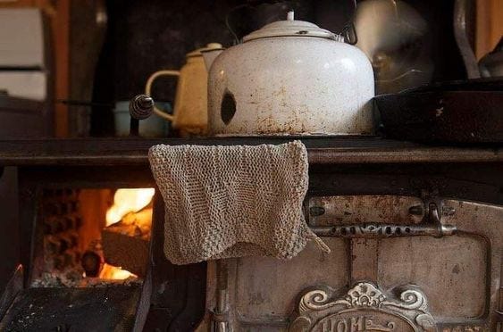 This may contain: an old fashioned stove with a tea kettle on it's burner and a towel hanging from the front