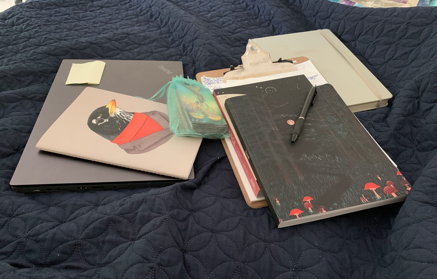 A computer, clipboard, and several journals spread out on the bed during my journaling session. 