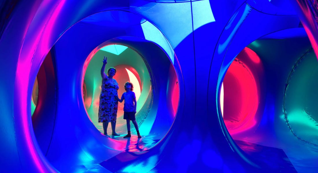 A blue inflatable dome with a woman and a child standing in one of the circular frames
