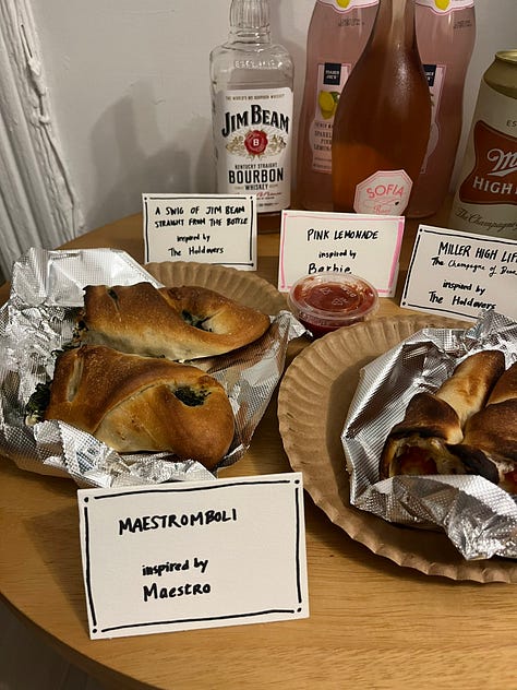 A dutch oven full of chili beside the label "Sloppenheimer," a stromboli behind a sign reading "Maestromboli," a plate of Almond Joys labeled "Da'Vine Almond Joy Randolph."