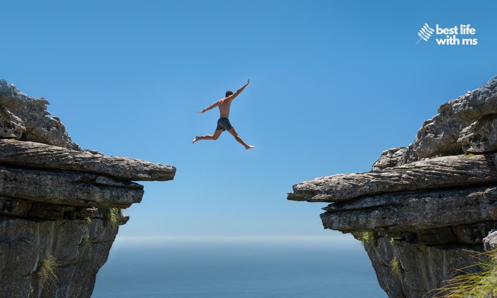 man in shorts jumps from rock ledge to another rock ledge and is pictured midair man in shorts jumps from rock ledge to another rock ledge and is pictured midair