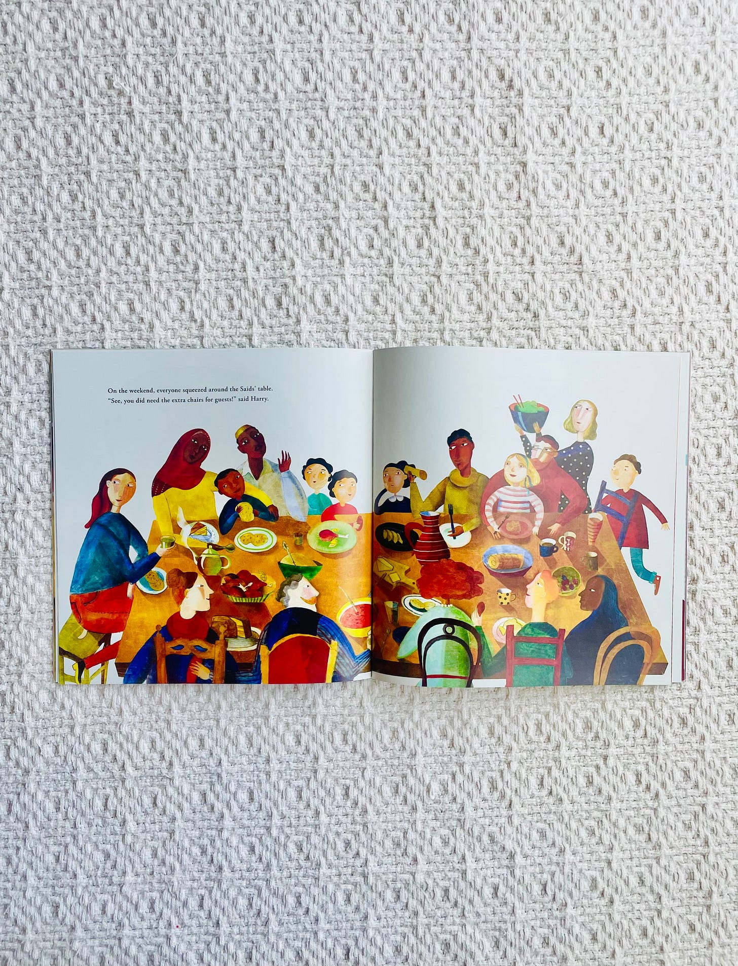 Open picture book with illustration of people gathering around table