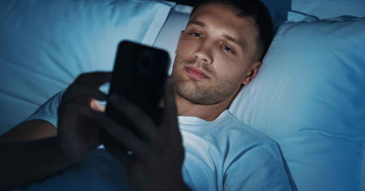  Man using smartphone in bed at night