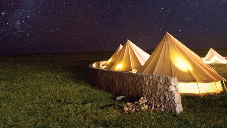 This may contain: two tents are set up in the middle of a field at night with stars above them
