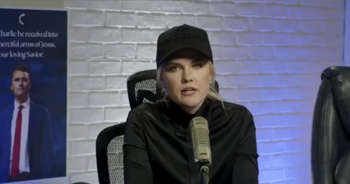 Woman wearing a black cap with the word "FREEDOM" speaks into a microphone during a podcast, with a poster of a man in a suit in the background.