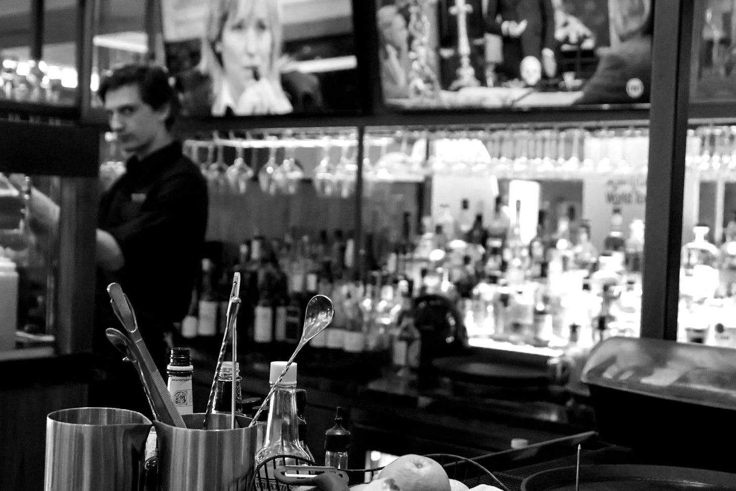 A man standing at a bar in front of a television A man standing at a bar in front of a television