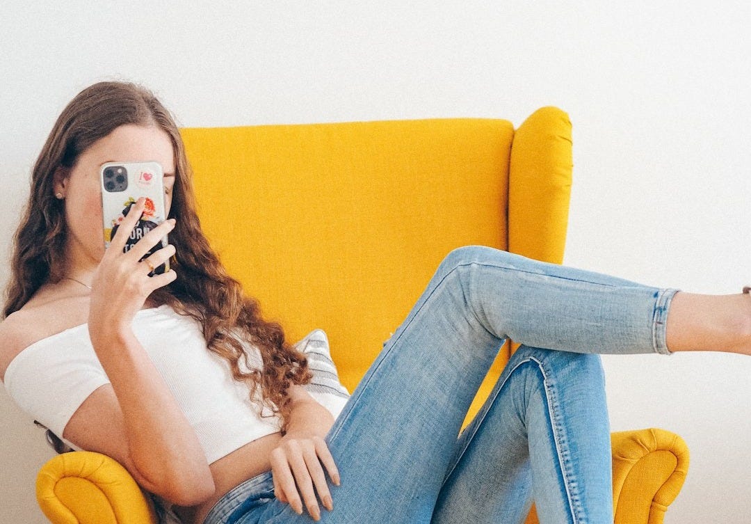 woman in white tank top and blue denim jeans sitting on yellow sofa