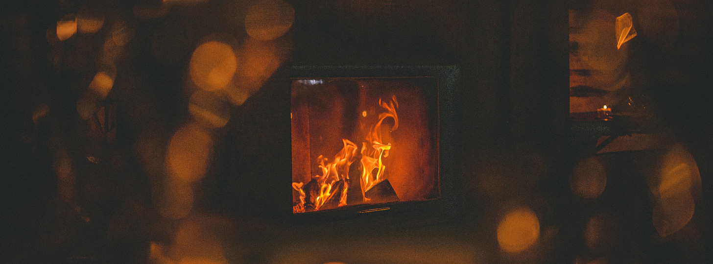A wood stove burns in the dark, there are traces of glowing lights around