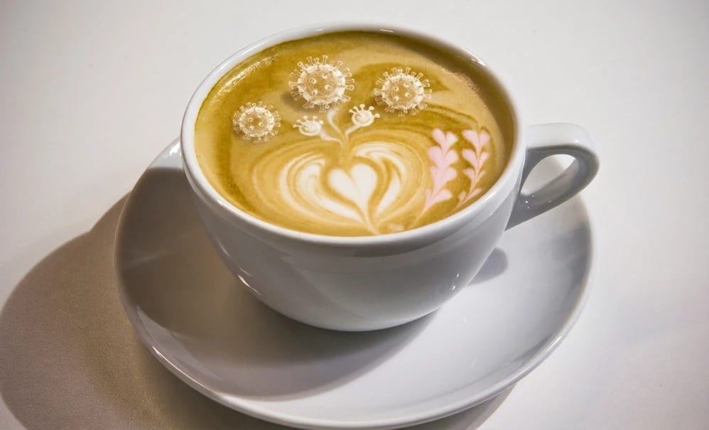 Picture of a flat white, but with some of the latte art modified to resemble archetypal coronaviruses. 