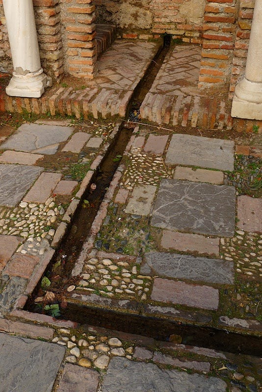 This may contain: an open drain in the ground between two stone pillars