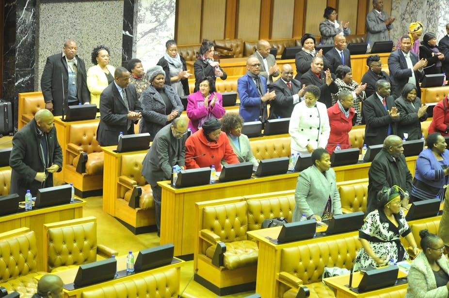 Men and women stand in rows of seating